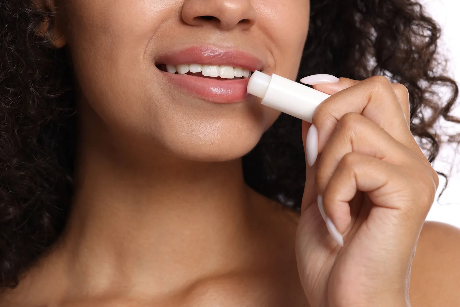 Close-up of a smiling woman applying a balm stick to her lips