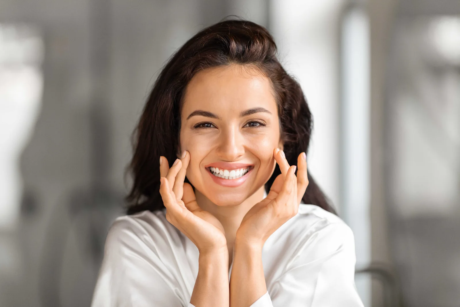 Smiling woman resting her hands against her cheeks after non-surgical treatment