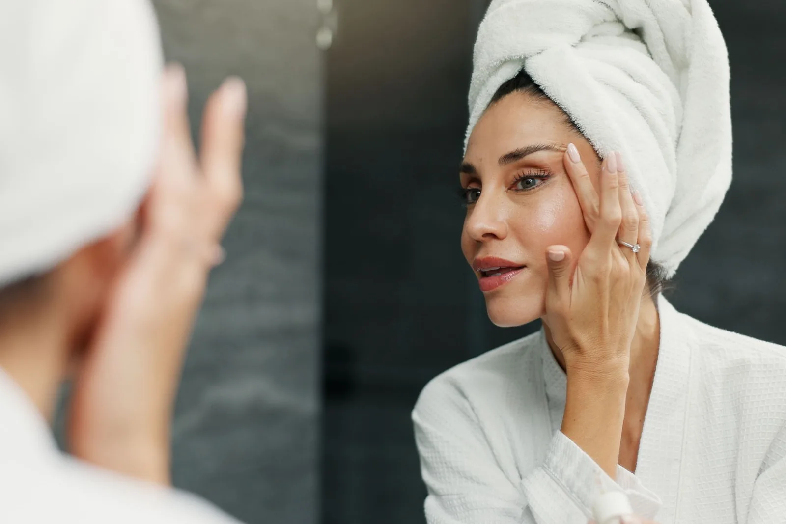 Woman checking her skin in the mirror during a morning skincare routine