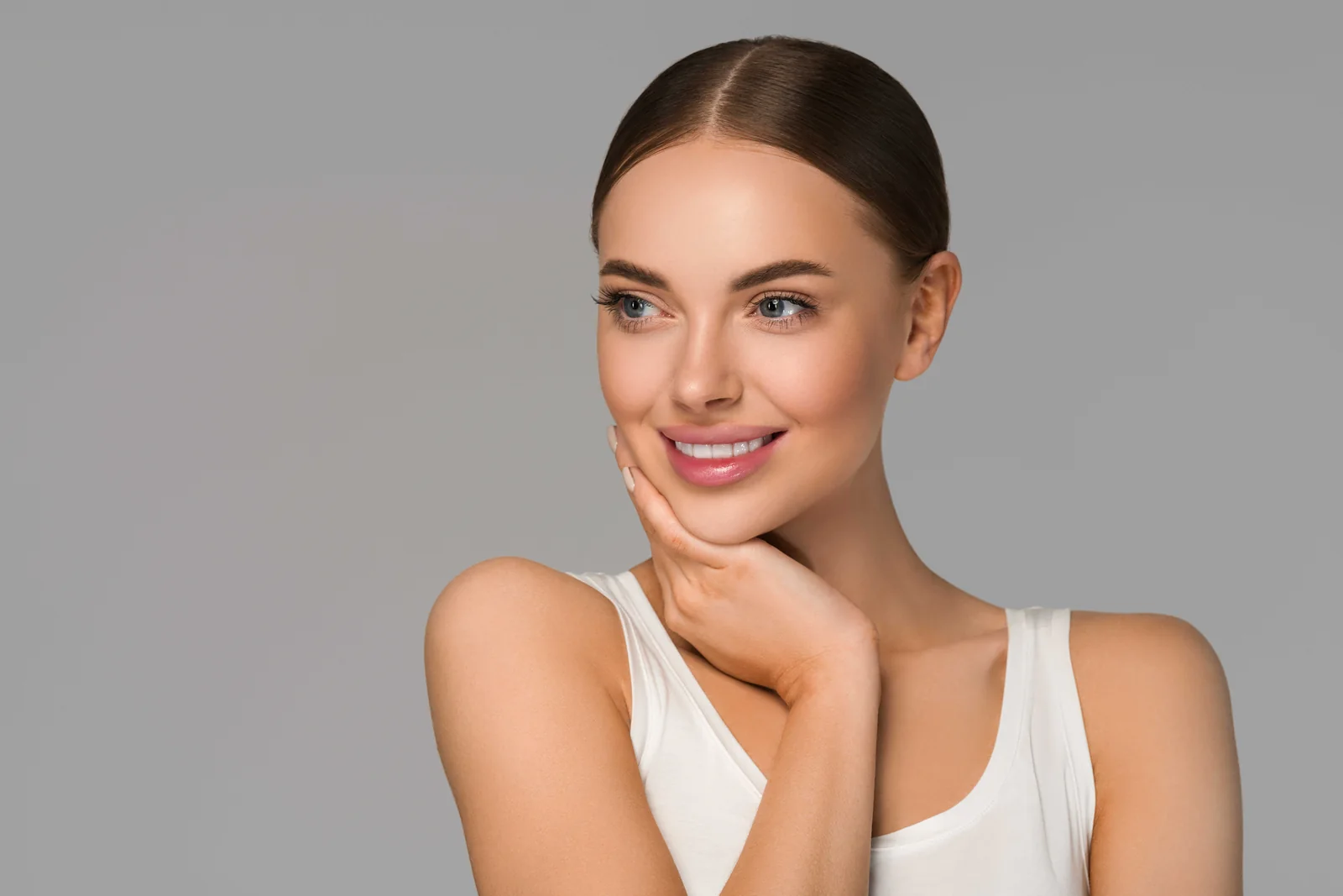 Woman with smooth, even skin resting a hand against her chin